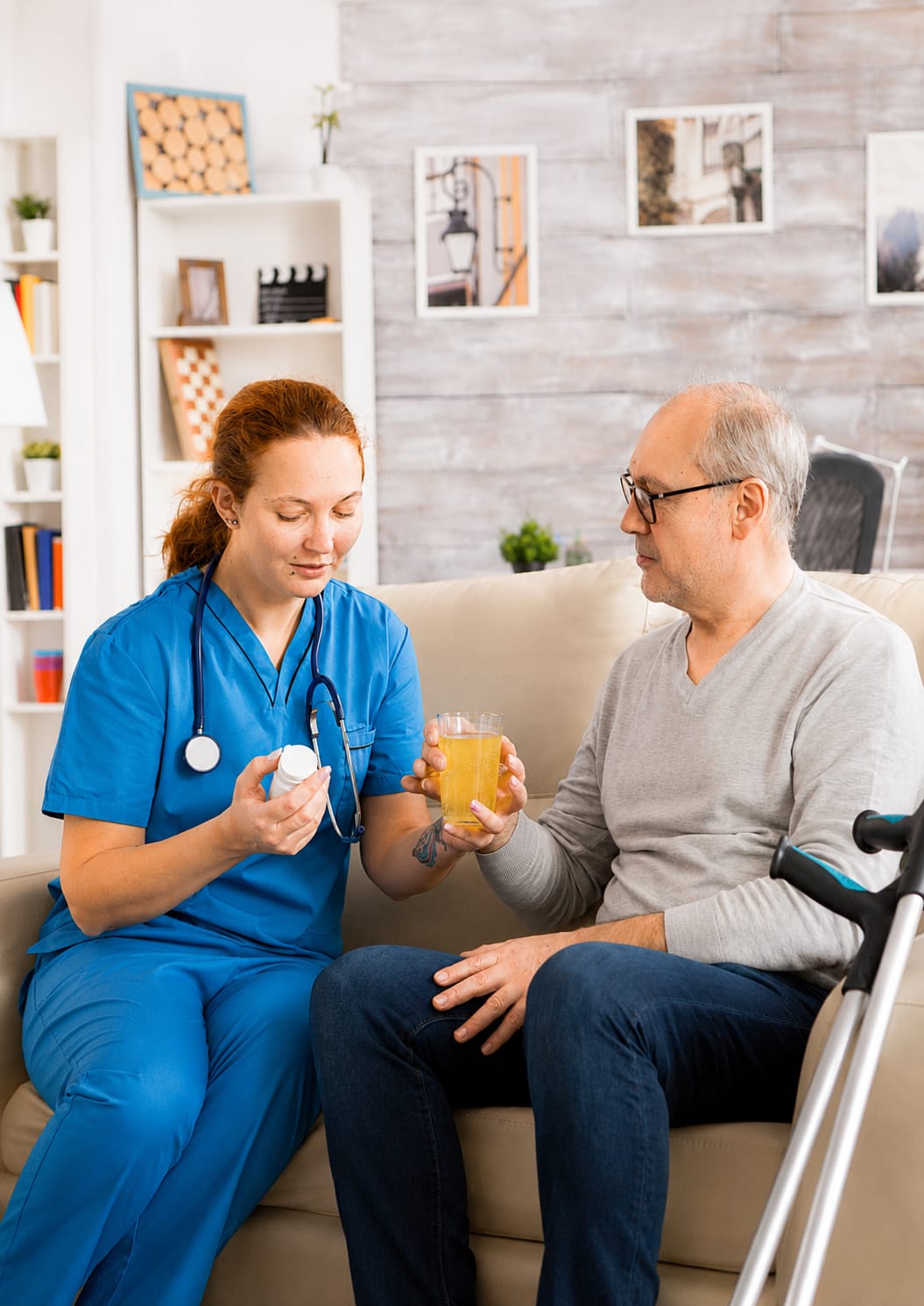 Nurse helping an elderly man drink water at home